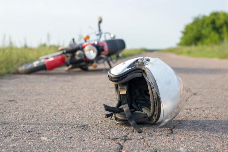 A damaged motorcycle and helmet at the scene of a motorcycle accident.
