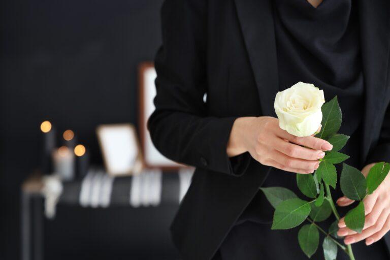 Grieving young woman with rose at funeral. A wrongful death lawyer can help her get compensation.